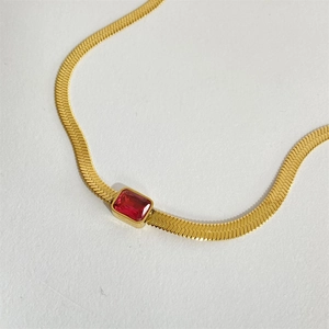 Golden snake chain necklace with a red rectangular zircon pendant on a white background