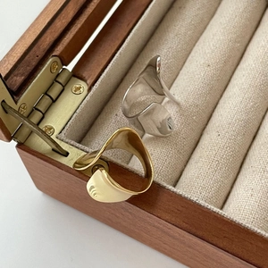 Close-up of minimalist gold and silver wavy rings in a luxury wooden jewelry box