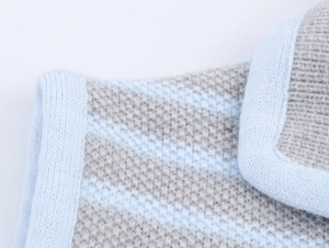 Dettaglio macro del gilet in maglia a righe azzurre e grigie con trama del tessuto fine