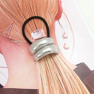Detail of silver U-shaped metal buckle on black elastic hair tie shown on a model hair card