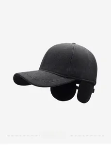 Detail of dark grey winter baseball cap featuring side ear flaps and metal shield ornament