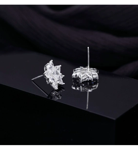Macro detail of silver snowflake earrings with sparkling cubic zirconia on black silk
