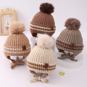 Detail of four colorful knit hats for children with pom-poms and earflaps on white stands