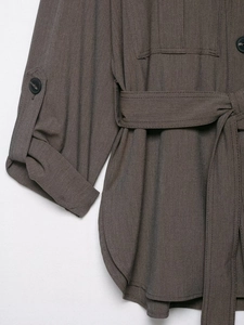 Détail du poignet réglable et de la ceinture sur la veste tissée de couleur gris-brun foncé