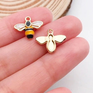 Vue macro de petits pendentifs abeille en émail pour bijoux DIY sur la paume d'une main
