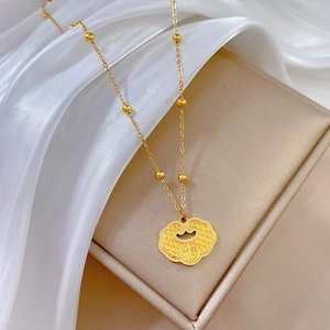 Detail of gold titanium steel necklace featuring a Fu character lock pendant on silk cloth