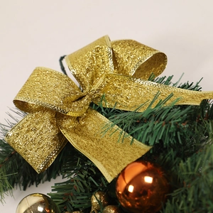 Golden glitter bow Christmas wreath ornament with orange baubles on pine needles