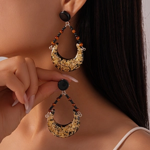 Retro crescent resin earrings with gold foil details worn by a model in a close-up view