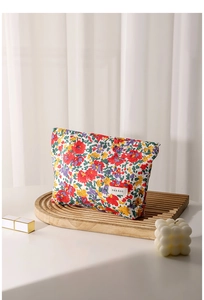 Macro detail of floral cotton toiletry bag with H&R BAG label on a wooden tray