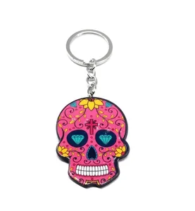 Close-up of pink Halloween skull keychain with blue diamond eyes and floral patterns