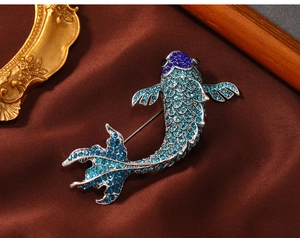 Detailed macro view of high-end blue rhinestone koi fish brooch on red velvet surface
