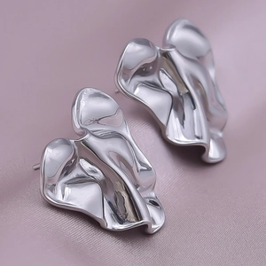 Macro shot of silver fluid wave earrings with high-polished stainless steel texture