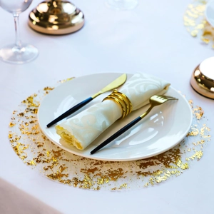 Close-up of golden round placemat with shimmering sequins and elegant black cutlery set