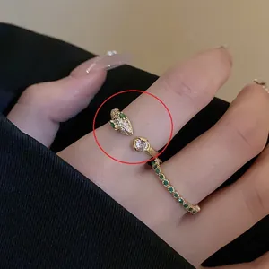 Macro detail of gold-plated snake ring featuring green gem eyes and a clear main stone