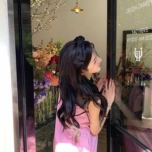 Side view of elegant black double-layered bow headband worn by a female model