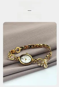 Detail of oval gold bracelet watch featuring a mother of pearl dial and bee charm