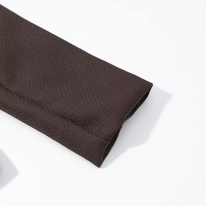 Detailed close-up of dark brown knitted fabric texture and folded cuff edge on clothing