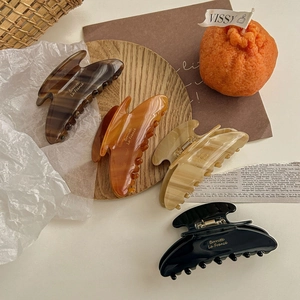 Brown and amber acetate large hair claws set on wooden tray with cozy minimalist styling