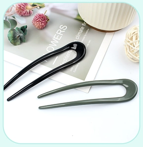 Detail view of U-shaped hair pins in black and dark green for elegant hair styling