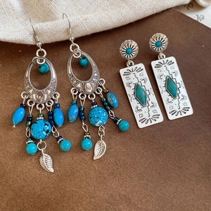 Macro detail of bohemian turquoise drop earrings with silver leaf tassels and tribal patterns