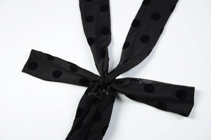 Close-up of black sheer mesh fabric with velvet polka dots and a tied ribbon detail