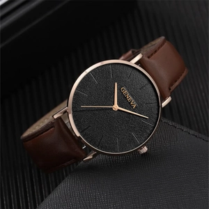Detail of a fashion quartz watch with textured black dial, gold hands and brown leather strap
