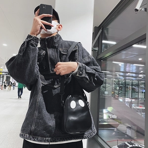 Close-up of a quirky ghost-shaped black PU leather crossbody bag on a denim jacket
