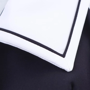 Detail shot of white twill fabric with black contrast binding and fine stitching work