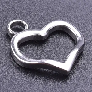 Macro shot of silver hollow heart-shaped stainless steel pendant on black textured surface