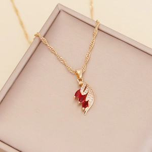 Close-up of golden feather necklace with red marquise gems and sparkling crystals