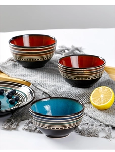 Detailed close-up of colorful ceramic Japanese rice bowls on a wooden tray with fruit decor