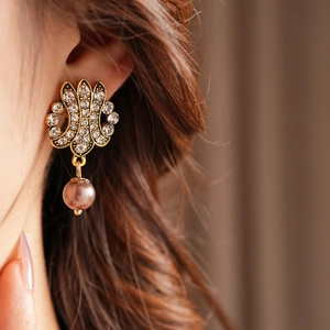 Detail of vintage gold earrings with rhinestones and a pearl pendant on a model