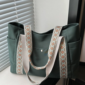 Dettaglio della borsa tote in tela verde scuro con ampie tracolle a motivi geometrici