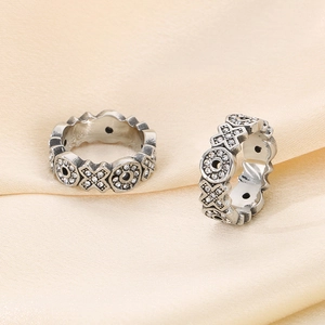 Macro shot of two vintage stainless steel rings with XO hollow patterns and inlaid zircons