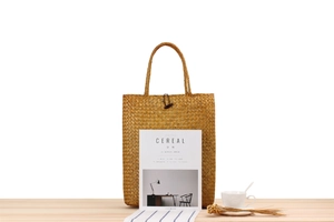 Detail of woven straw tote bag featuring a vintage wooden button closure and natural texture