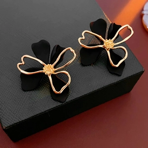 Close-up of gold and black layered flower earrings on a textured jewelry box