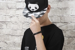 Close-up of baseball cap with geometric panda print and woven magnetic bracelet on model