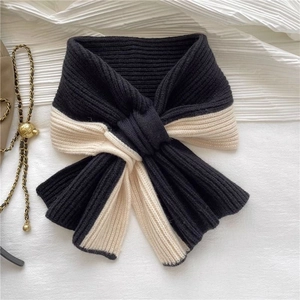 Detail of a black and white checkered knit scarf with a soft texture and knotted design