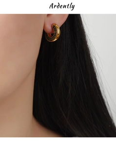 Detail of a vintage gold U-shaped earring set with green gems worn by a model