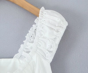 Detailed close-up of white eyelet lace embroidery and ruffle shoulder on cotton vest