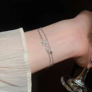 Detailed close-up of double-layer silver bracelet with snowflake and zircon charms on wrist