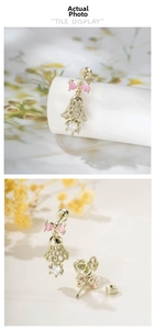 Close-up of pink bow earrings with hollow bell pendants and secure screw-back studs
