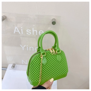 Detail of neon green PVC shell bag with pearl texture and golden metal chain