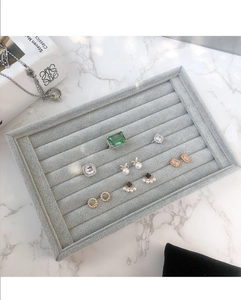 Détail macro du plateau à bijoux en velours gris clair sur marbre blanc élégant