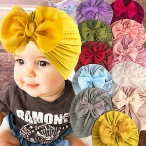 Detail view of colorful ribbed baby turban hats with large decorative bow accents