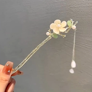 Détail macro d'une épingle à cheveux magnolia avec pompons dorés et perles
