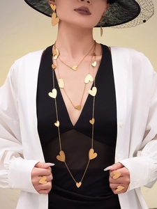 Detail view of a gold heart jewelry set including long necklaces, earrings and rings