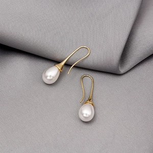 Elegant gold drop earrings with water drop pearls on a grey textured background