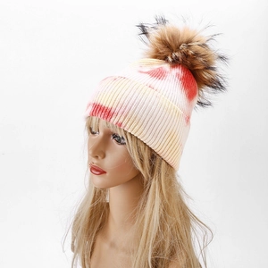 Women's tie-dye knit beanie with large faux fur pompom in red, yellow and white colors