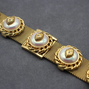 Macro detail of vintage gold mesh bracelet with iridescent pearls and micro rhinestones